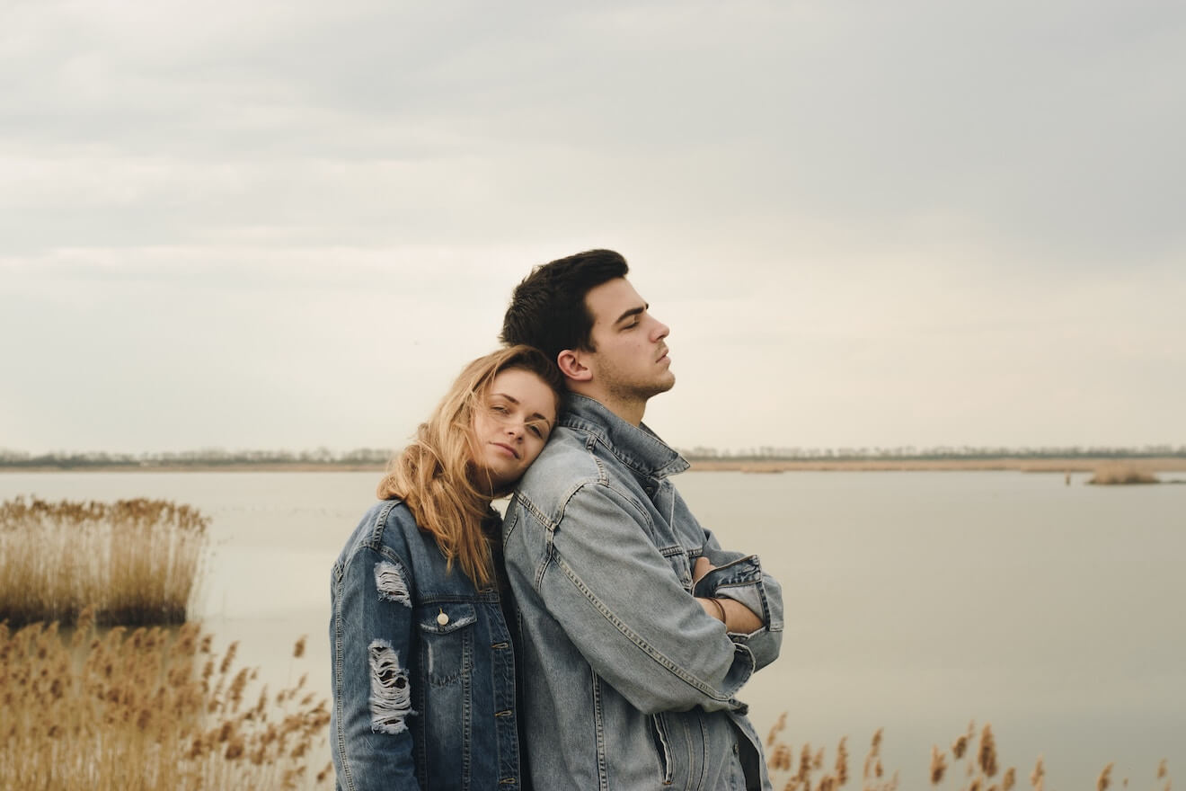 Couple standing by lake with man's back turned