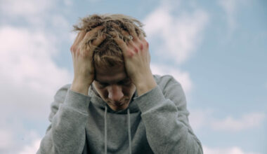 man in gray sweater sitting with face in his hands