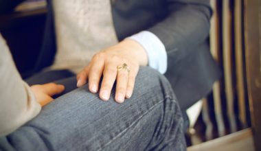 hand bearing a ring on someone's lap