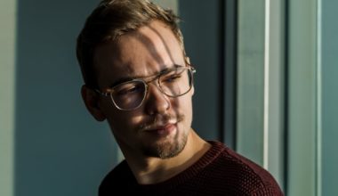 Shadows fall on a young guy's face as he gazes out the window