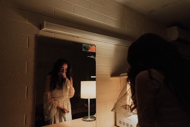 A woman cries while looking into the mirror.