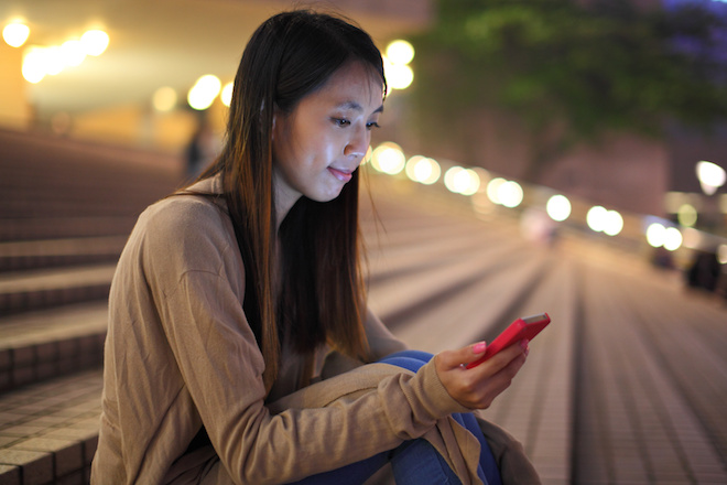 woman using phone in city at night