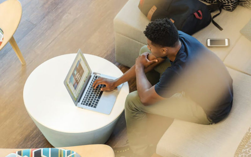 man sitting with laptop and phone looking puzzled