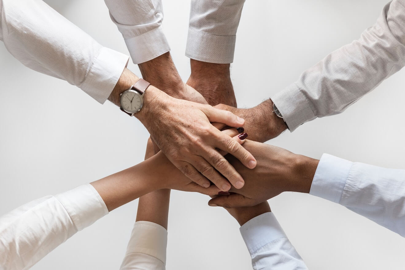 A group of people puts their hands in a circle