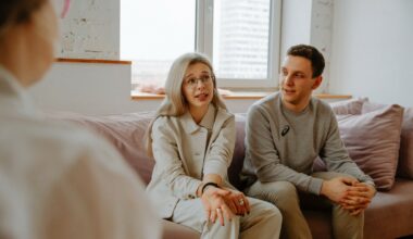 couple sitting on pink couch speaking to therapist