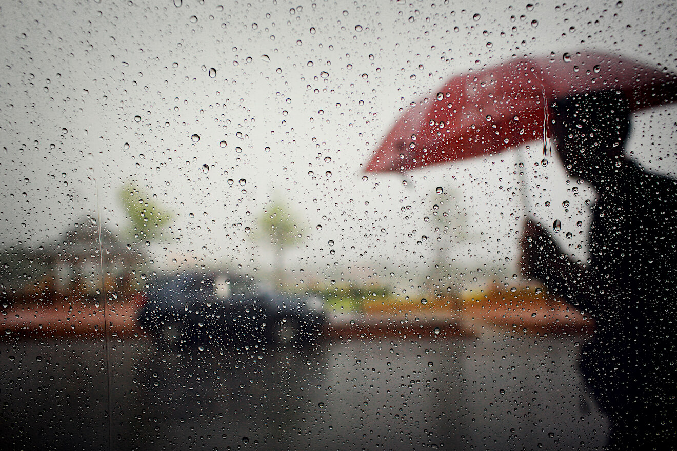 Blurry red umbrella behind rainy window