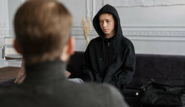 boy in black hoodie sitting across from man