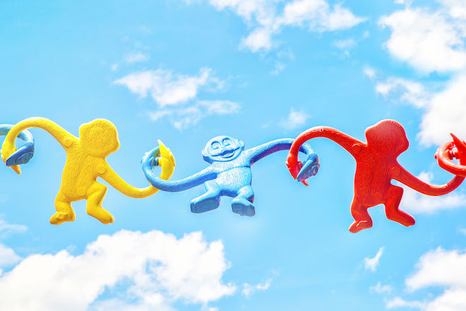 A group of toy monkeys linked in front of the sky