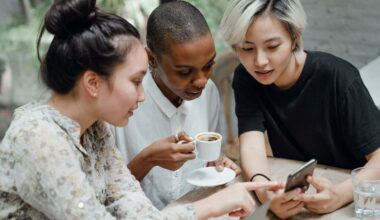 3-women-sitting-at-table-looking-at-phone