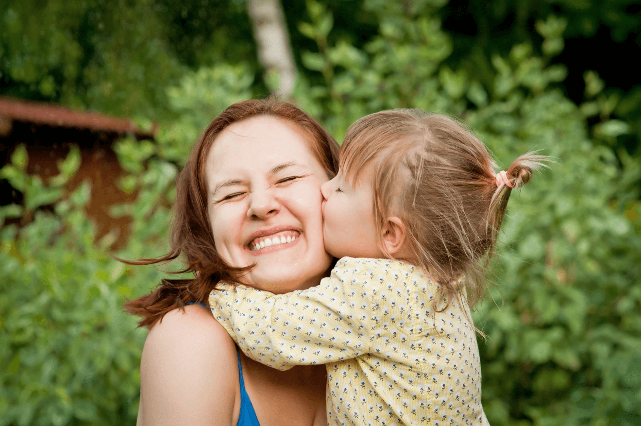 young daughter kissing mother's cheek