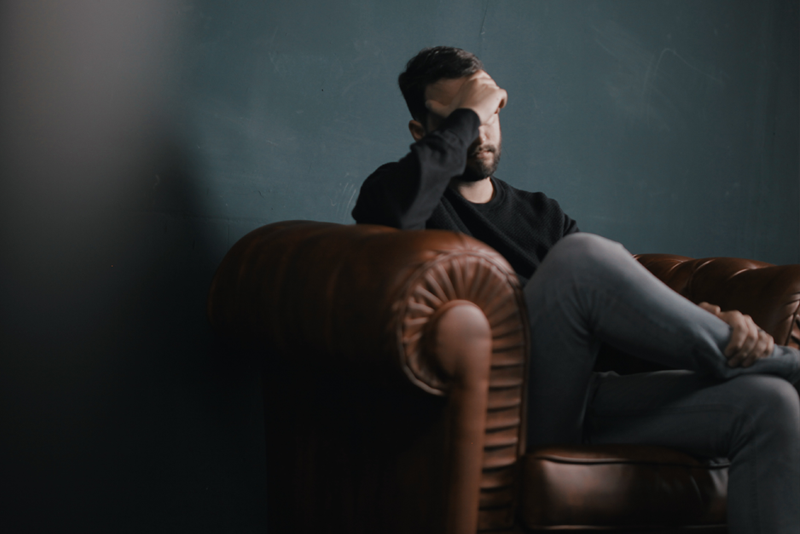 Man on leather chair with his head in his hand