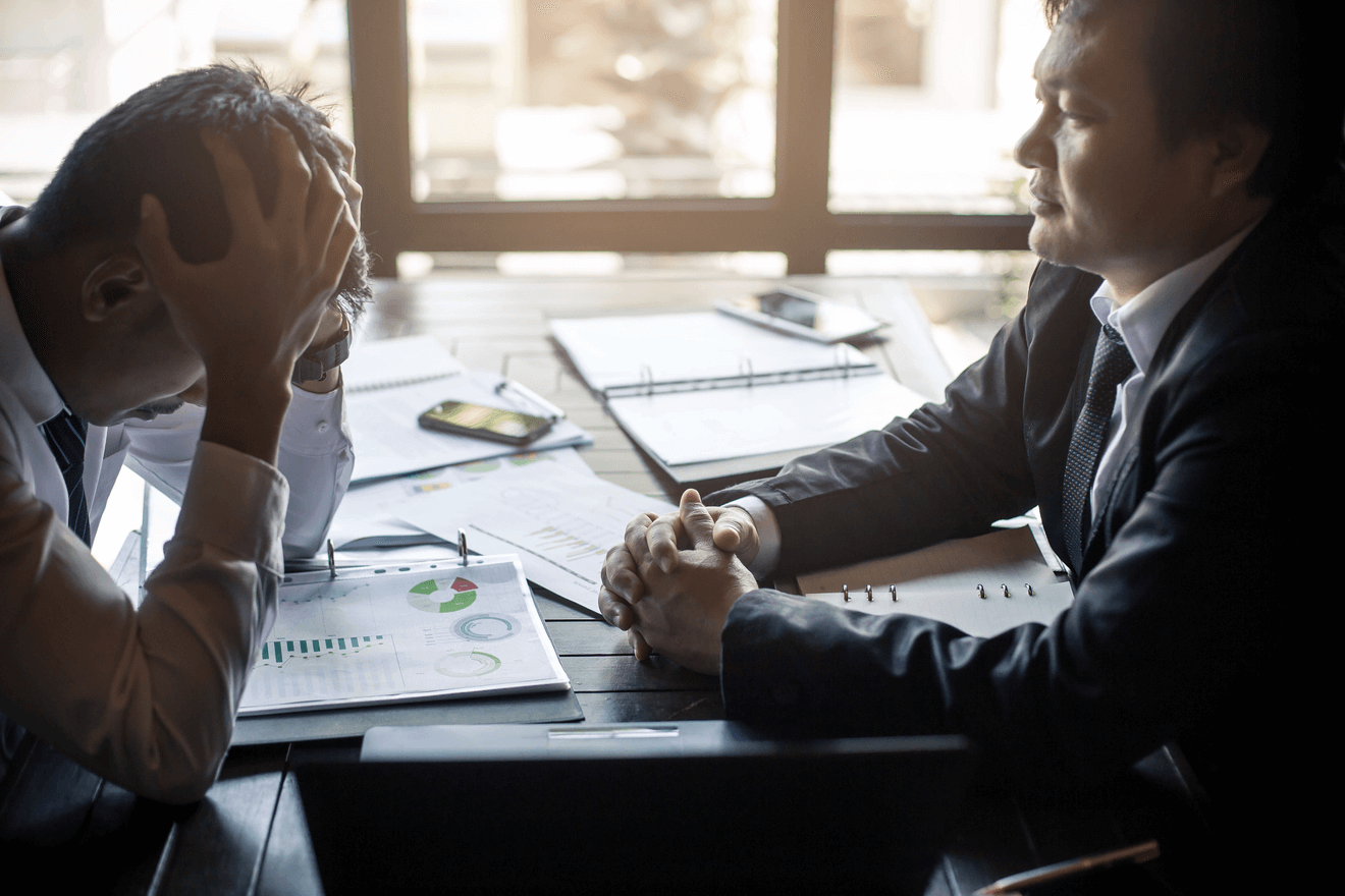 man with head in hands across from boss