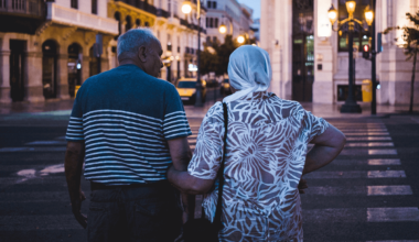 older couple holding hands crossing street