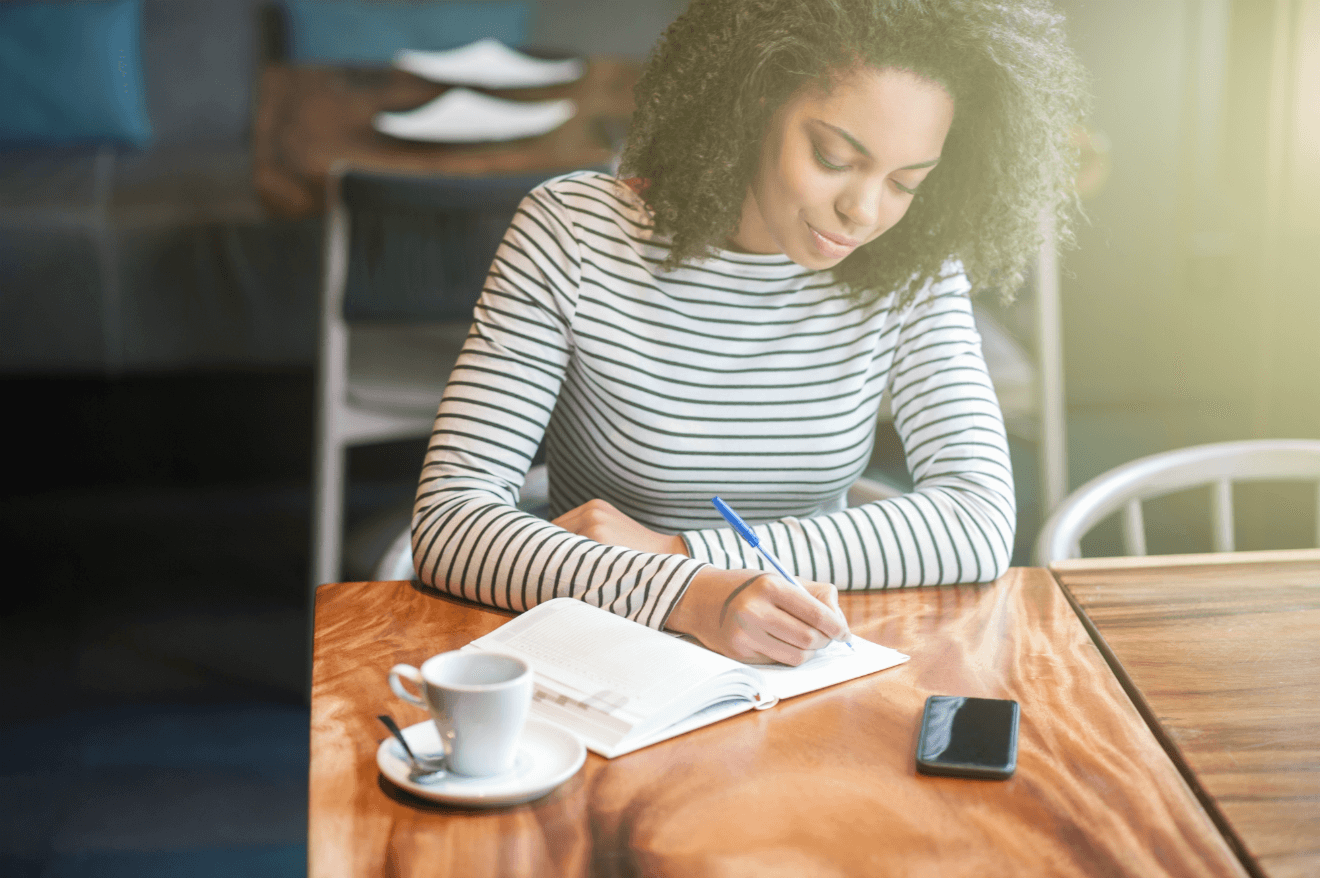 woman journaling on table with coffee