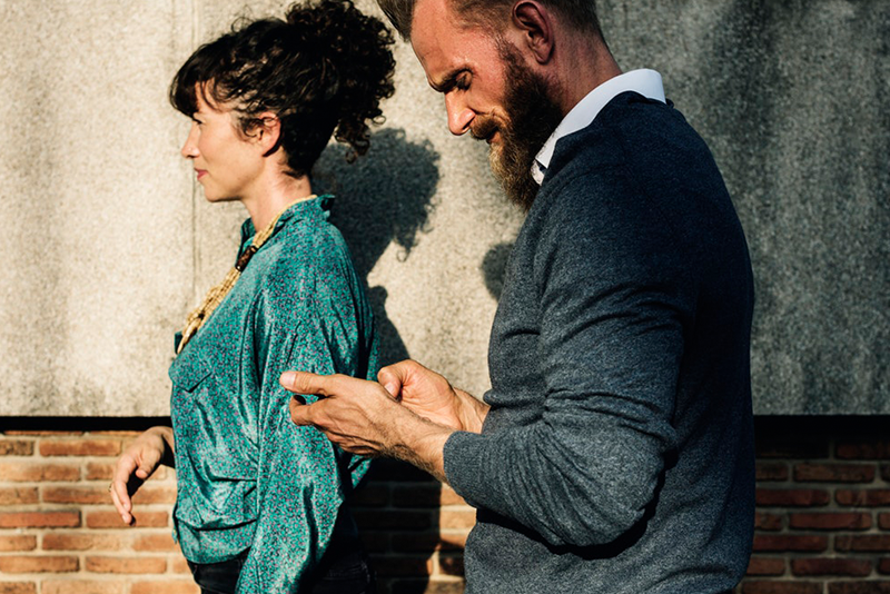 A couple walking with the man on his phone