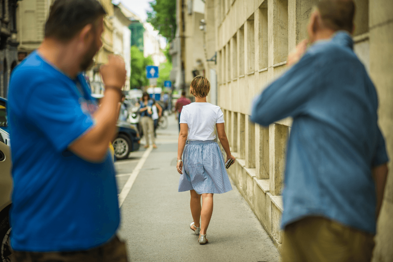 two men cat calling woman on street