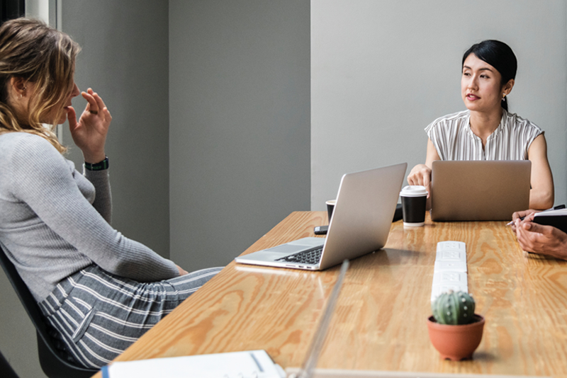 Women talking with laptops in front of them