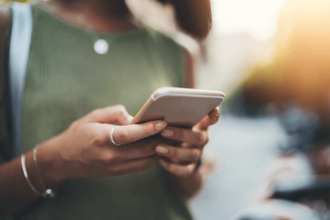 woman walking outside holing smartphone texting