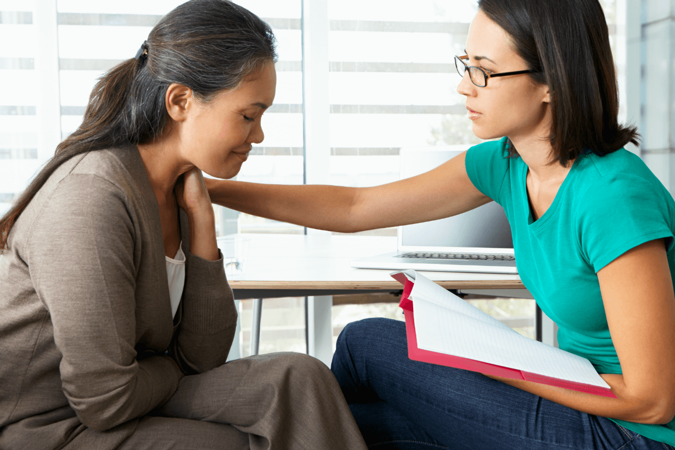 female therapist holding folder comforting woman client