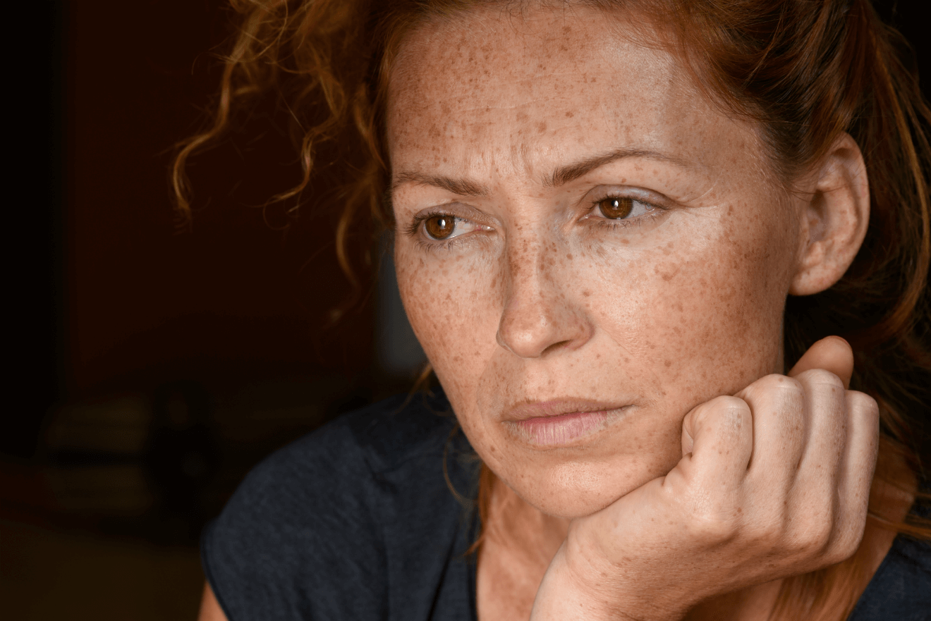 worried red headed woman with hand on chin